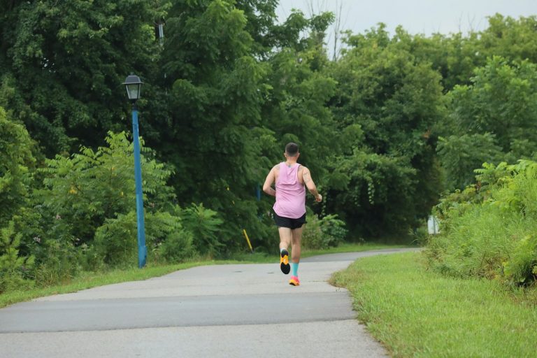 A woman running down a road in a pink shirt